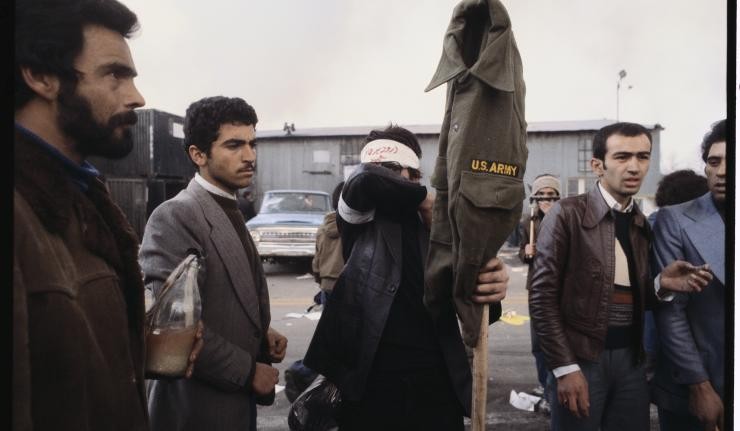 Iranian rebels holding up a US Army uniform on a stick likely ready to torch it Iranian rebels holding up a US Army uniform on a stick likely ready to torch it
