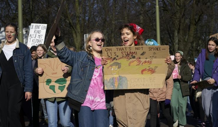 White climate protestors holding comic messages