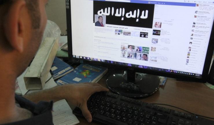Man viewing ISIS' facebook page on his desktop monitor Man viewing ISIS' facebook page on his desktop monitor