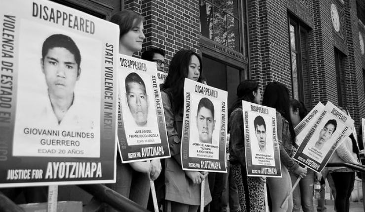 Protestors holding up signboards with images of persons disappeared due to state violence in Mexico
