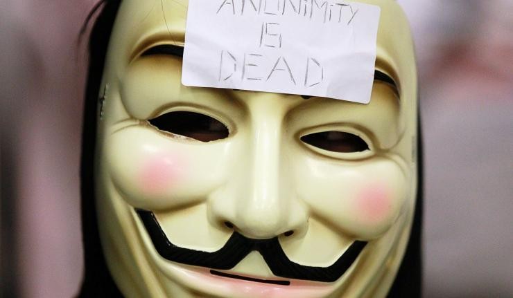 Man wearing face mask associated with the hacker group Anonymous with a Post-it labelled Anonimity is dead Man wearing face mask associated with the hacker group Anonymous with a Post-it labelled Anonimity is dead