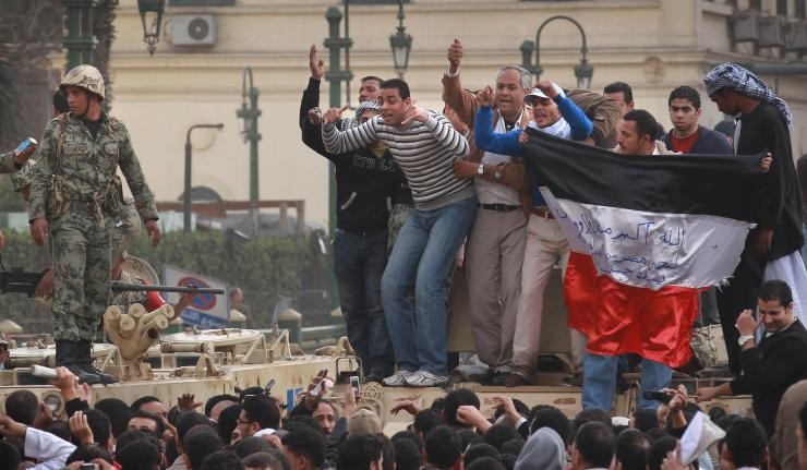Arab Spring Protestors standing off with the Police holding up an inverted tricolor flag of black, white and red
