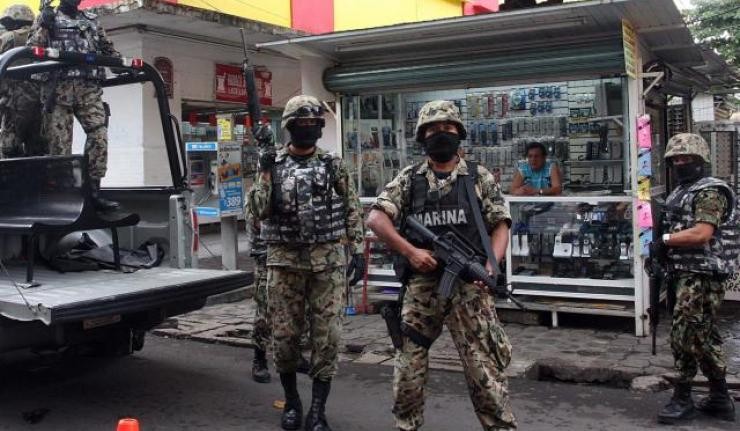 Mexican military police wearing bullet proof vests and holding up rifles