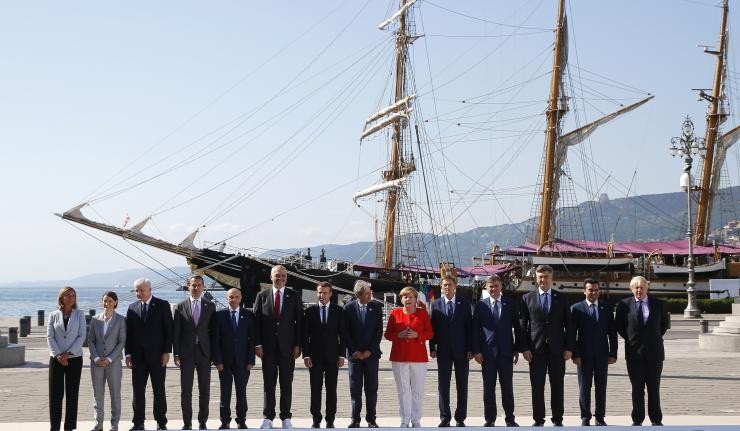 Heads of states of all EU governements standing in a row with a ship in the background