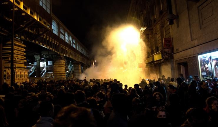 Mob setting off a smoke flare in a crowded city square