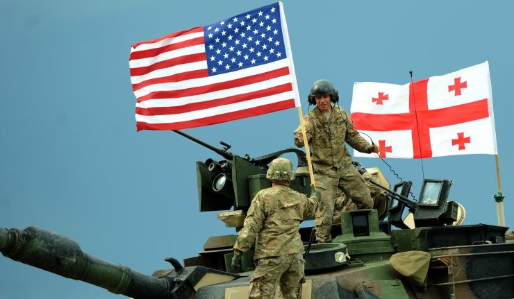 Soldiers atop an army tanker carrying both U.S. and Georgian flags