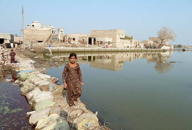 A young girl walks across a makeshift path through stagnant flood-water in Sindh province, Pakistan.