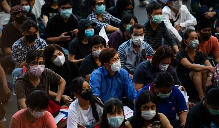 A crowded gathering of several individuals who are seated and wearing masks