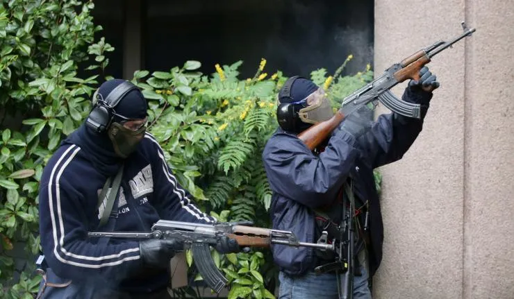 Two terrorists carrying rifles wearing masks, goggles, head gear and ear muffs