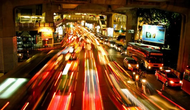 Timelapse image of cars cruising through a crowded Asian city, likely Bangkok