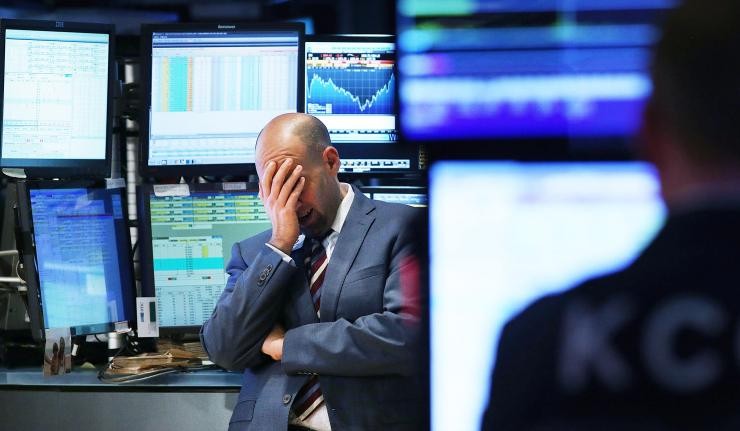 Trader in dealing room placing palm on face in anguish