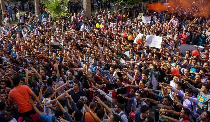 Youth raising their hands, setting off smoke flares and lifting a fellow protestor 