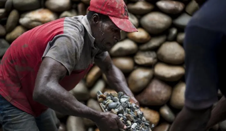 A miner at work holding up a container full of stones