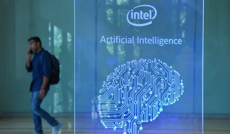 An engineer walking past a plaque which reads 'Intel Artificial Intelligence'