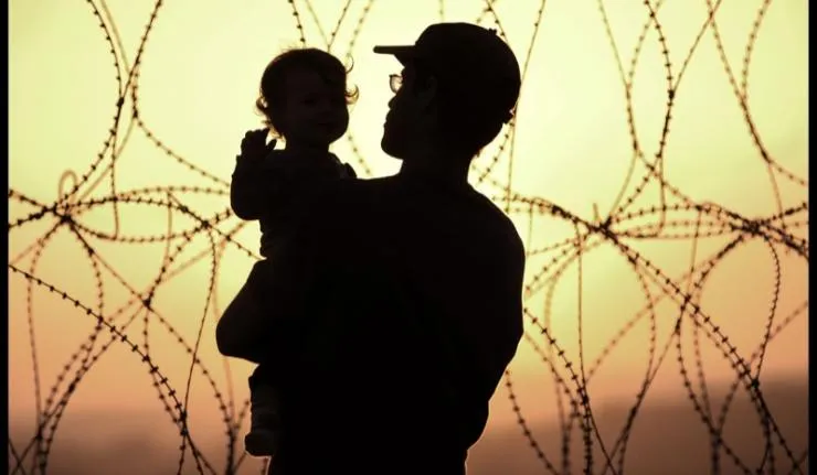 Sihouette of man carrying child at Gaza border