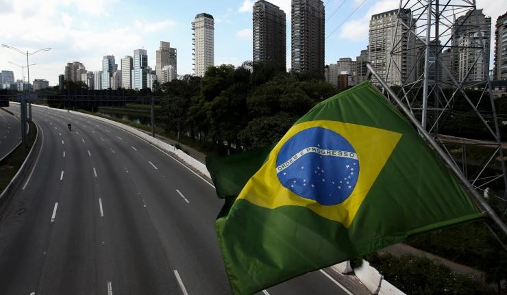A Brazilian flag with a skyline in the background