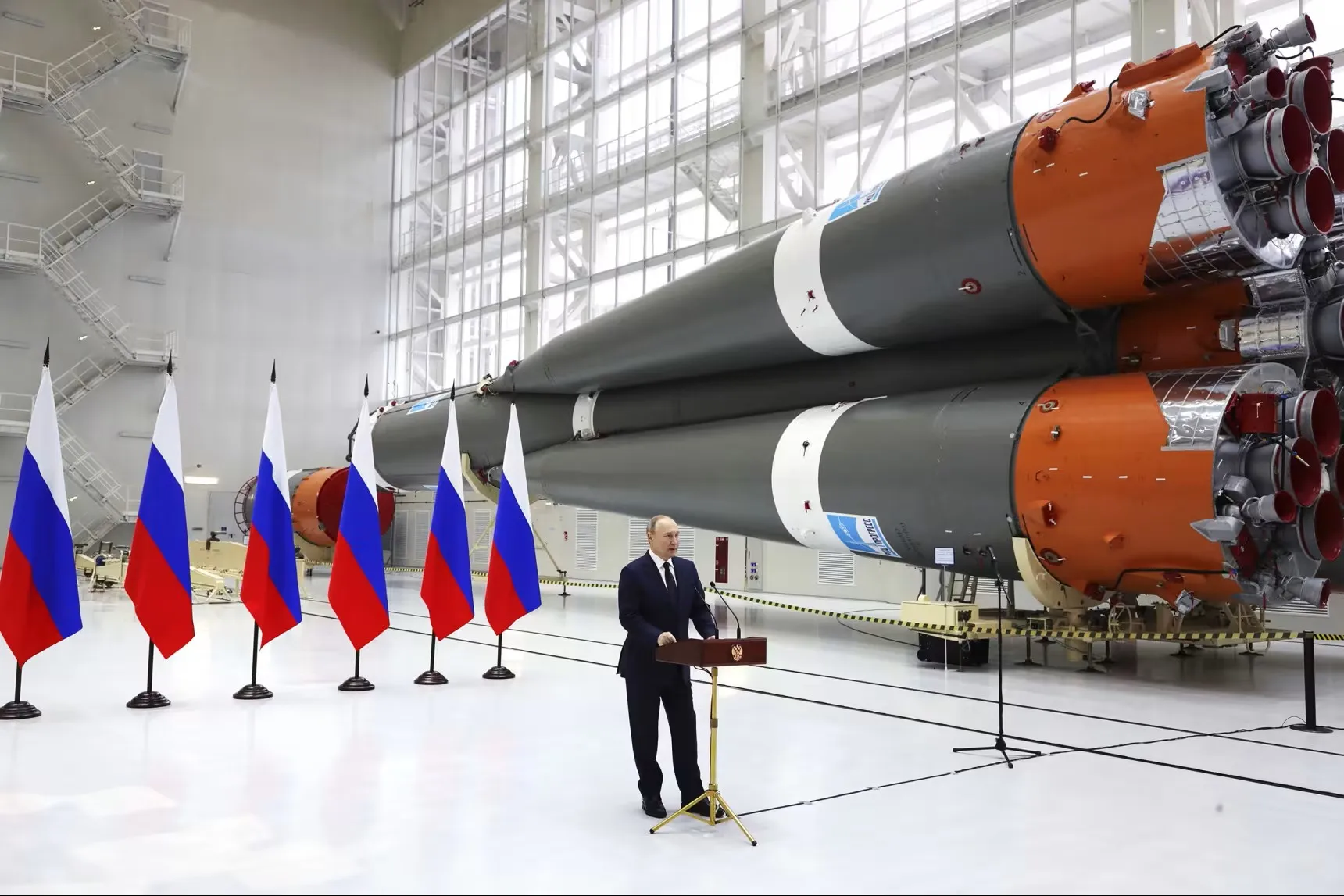 Vladimir Putin in front of Russian flags and nuclear missiles. 
